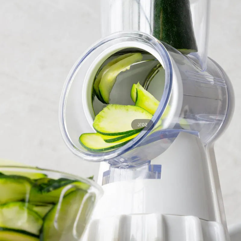 White 3-in-1 manual vegetable slicer and grater with suction feet on a kitchen counter.
