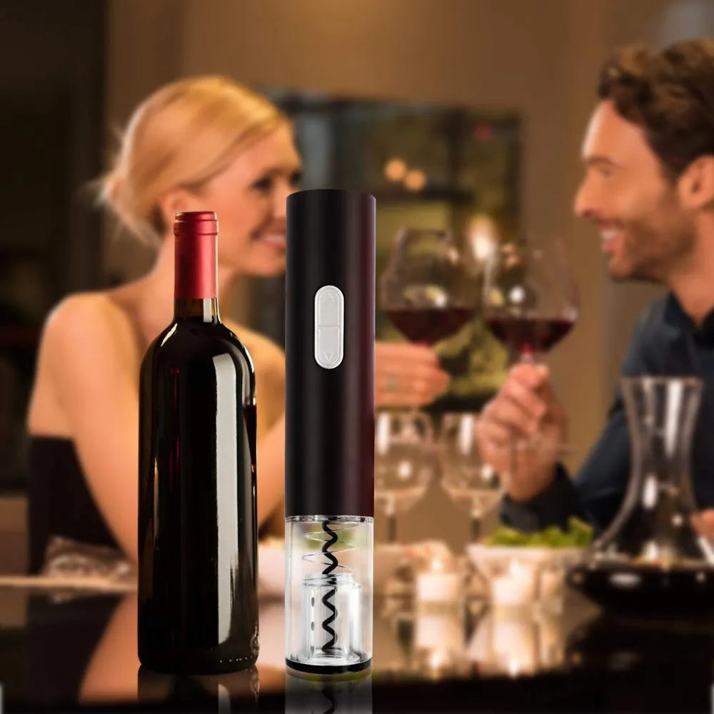 Black automatic electric wine bottle opener with foil cutter on a wooden table next to a wine bottle.