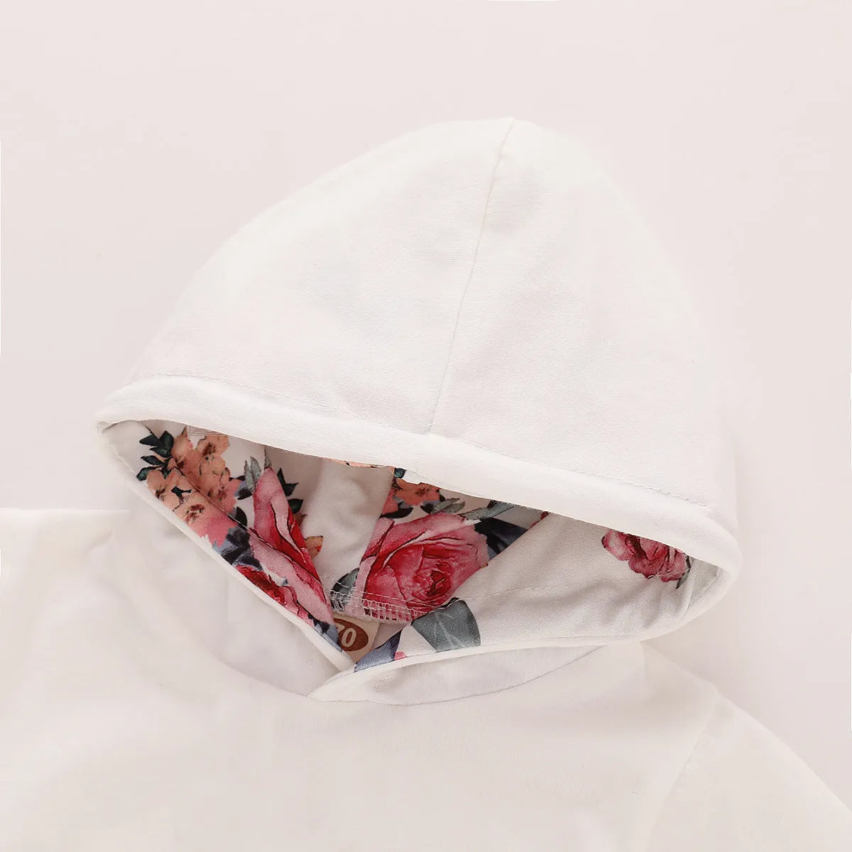 White cotton hooded tracksuit romper for a baby girl, showing long sleeves and full-length trousers.