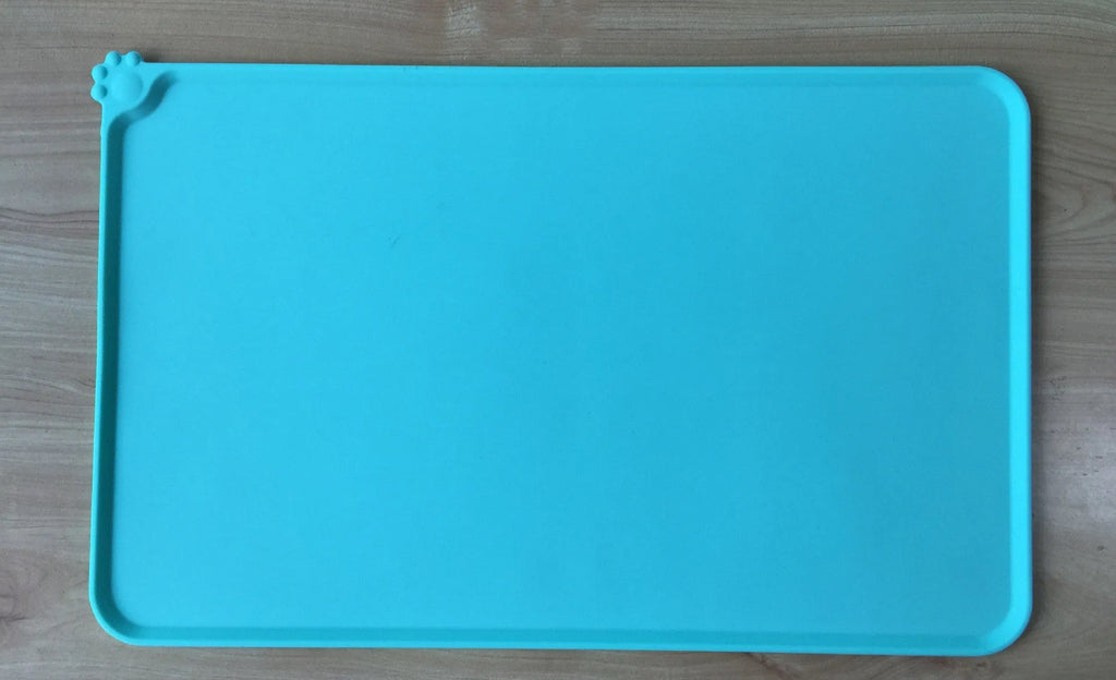 Black silicone dog food mat measuring 47 by 30 centimetres with non-slip surface and raised edges.