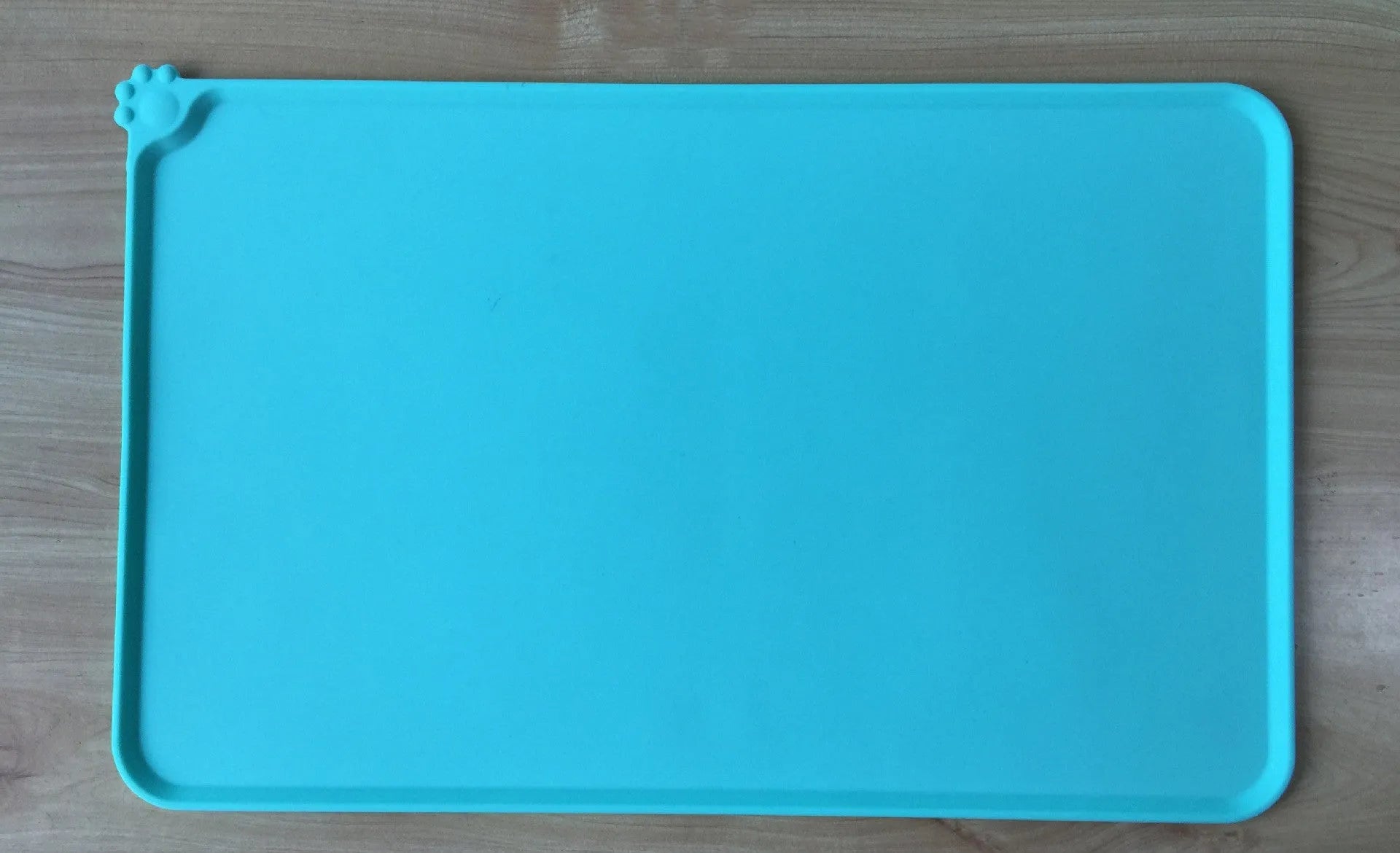 Black silicone dog food mat measuring 47 by 30 centimetres with non-slip surface and raised edges.