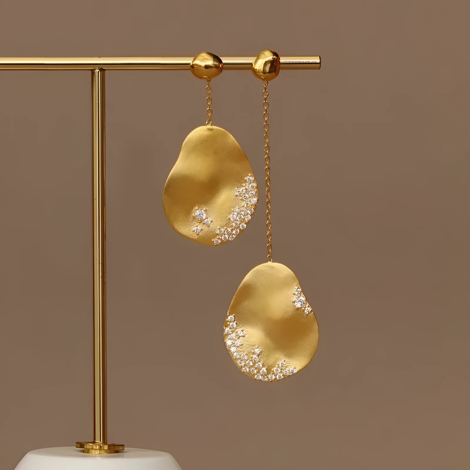 A pair of asymmetric gold-plated flower earrings with zircon detail, shown in silver and gold colour options.