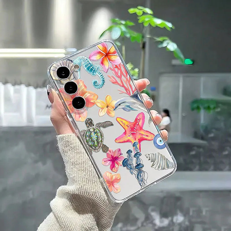 Clear transparent iPhone case with printed blue dolphin, green turtle, shell, and leaf designs.
