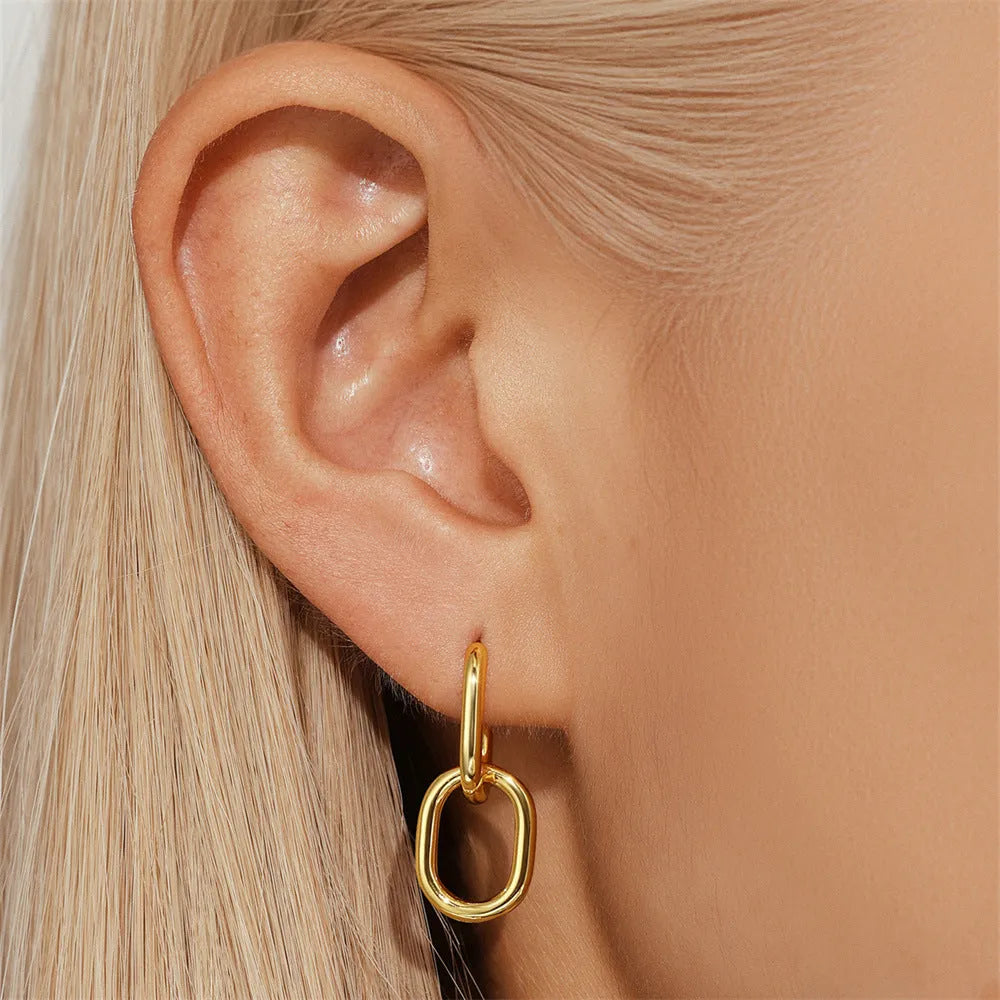 A pair of round geometric brass clip earrings with a gold electroplated finish on a white background.
