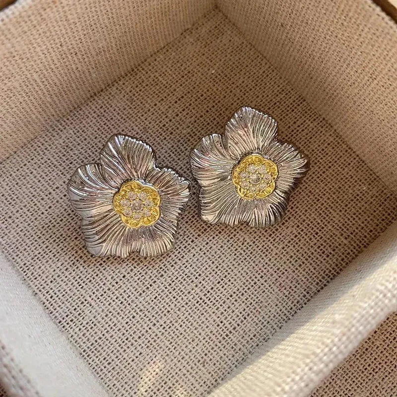 Close-up of retro textured gardenia stud earrings in two-tone copper with floral petal detail.