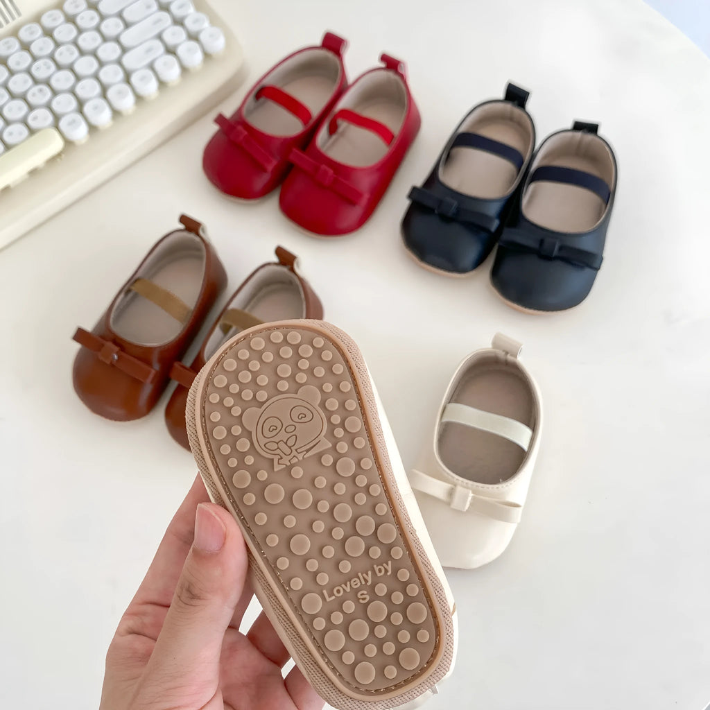 Women's soft non-slip PU low top baby shoes in black with bow detail on white background
