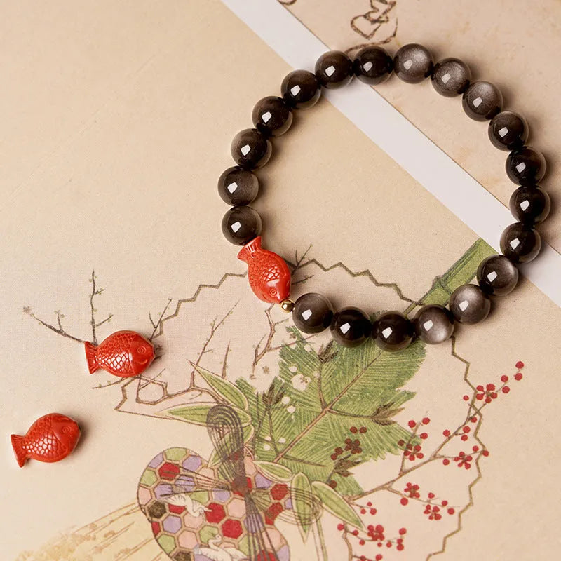 Natural obsidian bracelet with round beads and red cinnabar fungus decoration on wrist