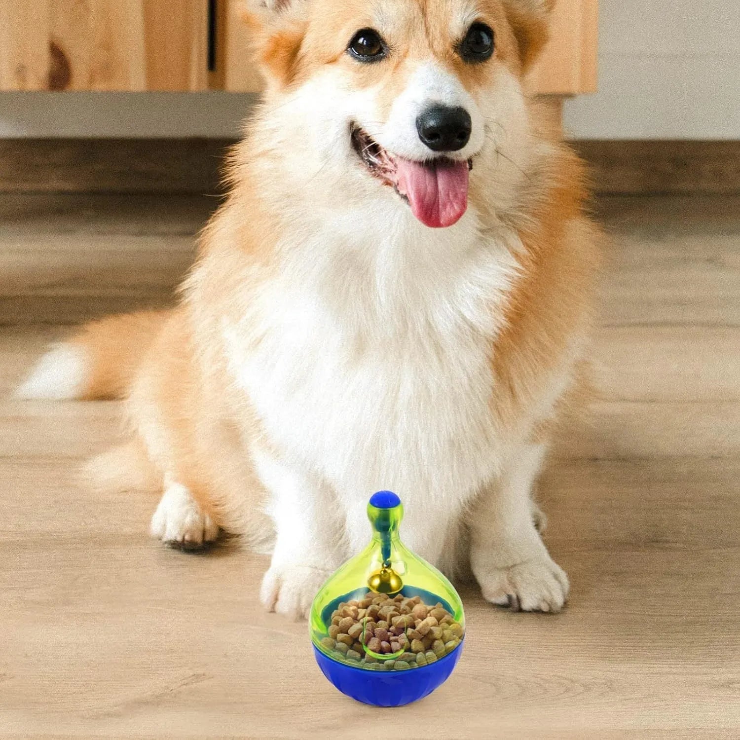 Blue and white tumbler-shaped plastic pet treat dispenser ball on a wooden floor.