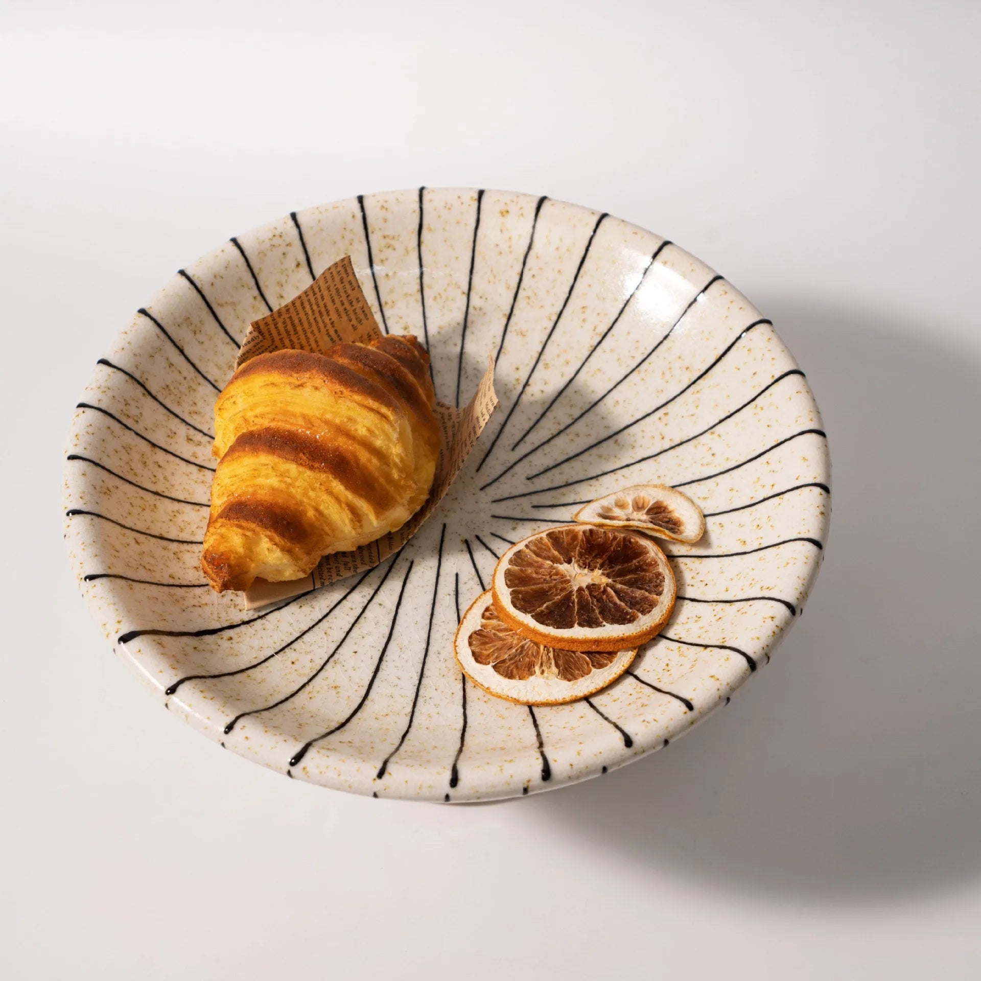 Black and white striped synthetic resin fruit plate on a plain surface.