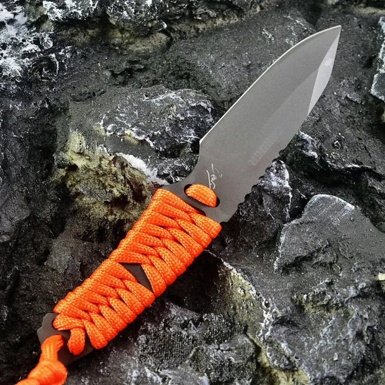 Straight blade outdoor survival knife with binding rope handle next to ABS plastic sheath