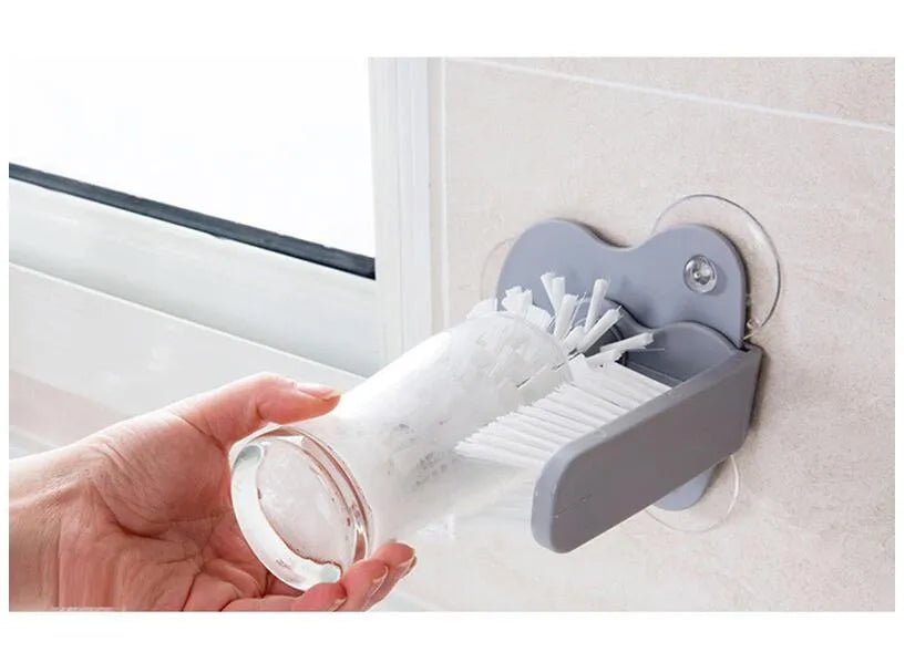 Grey rotating cup brush with two suction cups for wall mounting, shown cleaning a glass