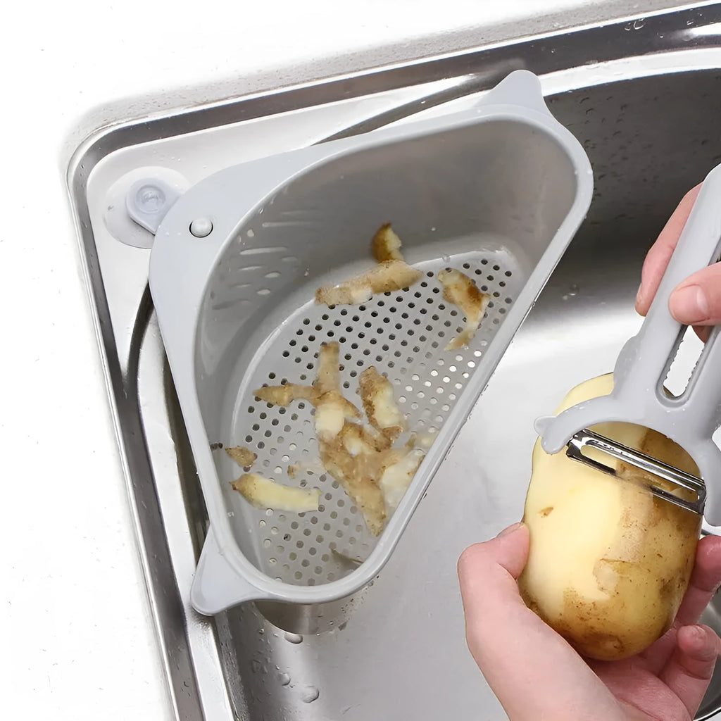 Triangular beige plastic kitchen sink storage rack with suction cup mount holding a sponge.