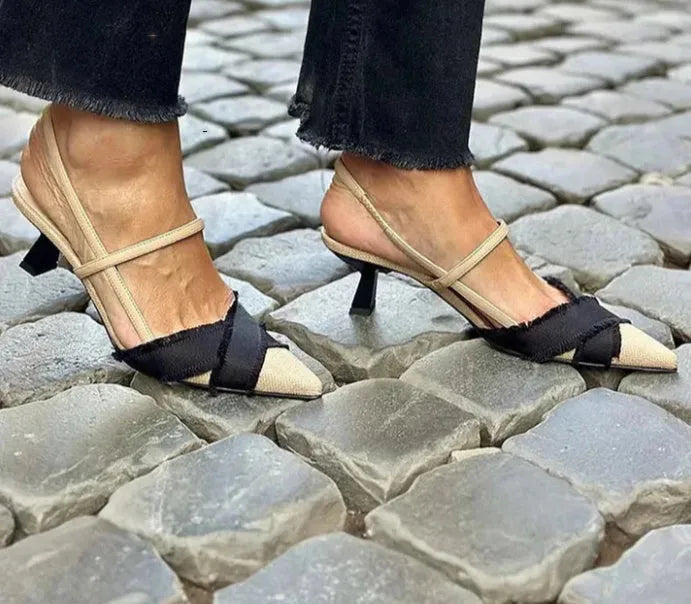 Apricot and black women's pointed toe stiletto heel sandals with a buckle strap.