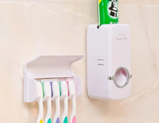 White bathroom accessories set with toothpaste dispenser and toothbrush holder mounted on smooth tile surface