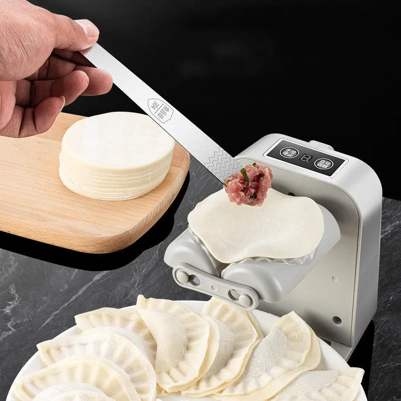 White automatic electric dumpling maker machine with USB cable and accessories on a kitchen counter.