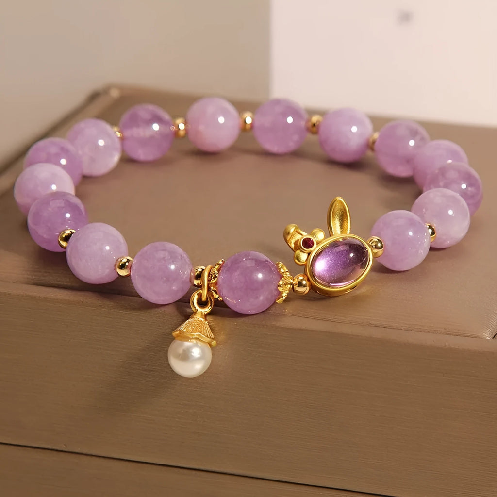 Mauve jade rabbit bracelet with a purplish red jade hare head charm on a crystal band.