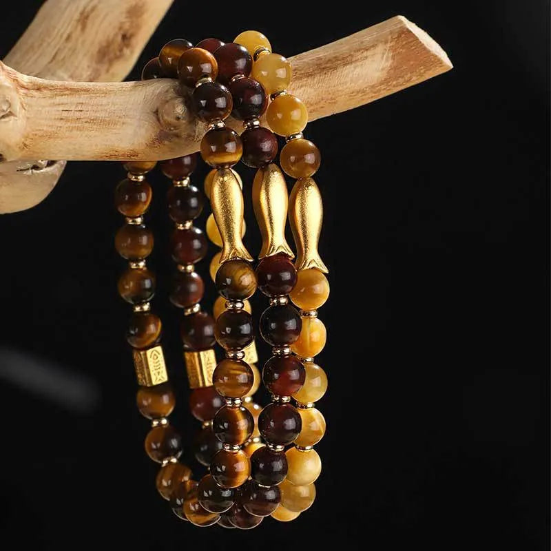 Close-up of a yellow tiger eye beaded bracelet with a detailed small fish charm.