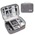Black and grey waterproof travel cable organiser bag open, showing mesh pockets and removable padded dividers inside.