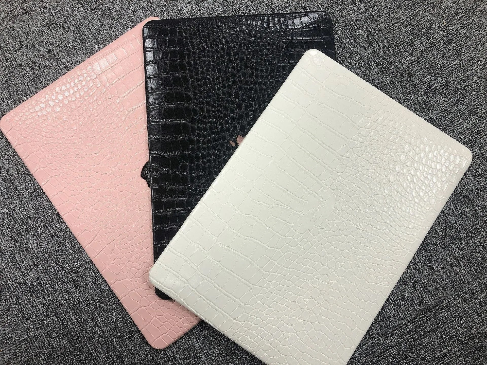 MacBook laptop case with crocodile pattern texture in black, white, or soft pink, showing hollowed Apple logo.