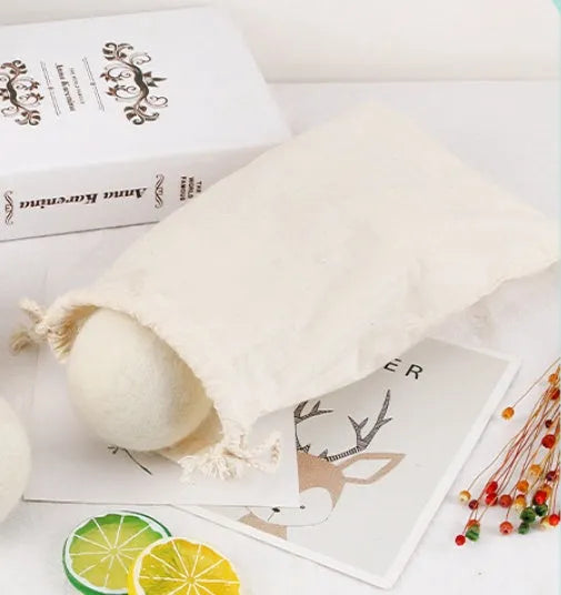 A wool drying ball for laundry next to a plain cotton storage bag on a background.