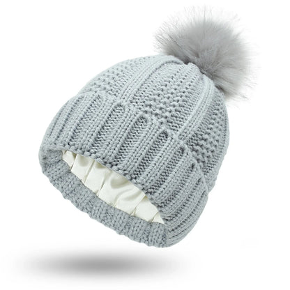 Cozy knit beanies with satin lining, paisley pattern, and faux fur pom poms in a variety of colors