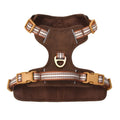 Brown leather dog harness with reflective strips and D-ring attachment on wooden background