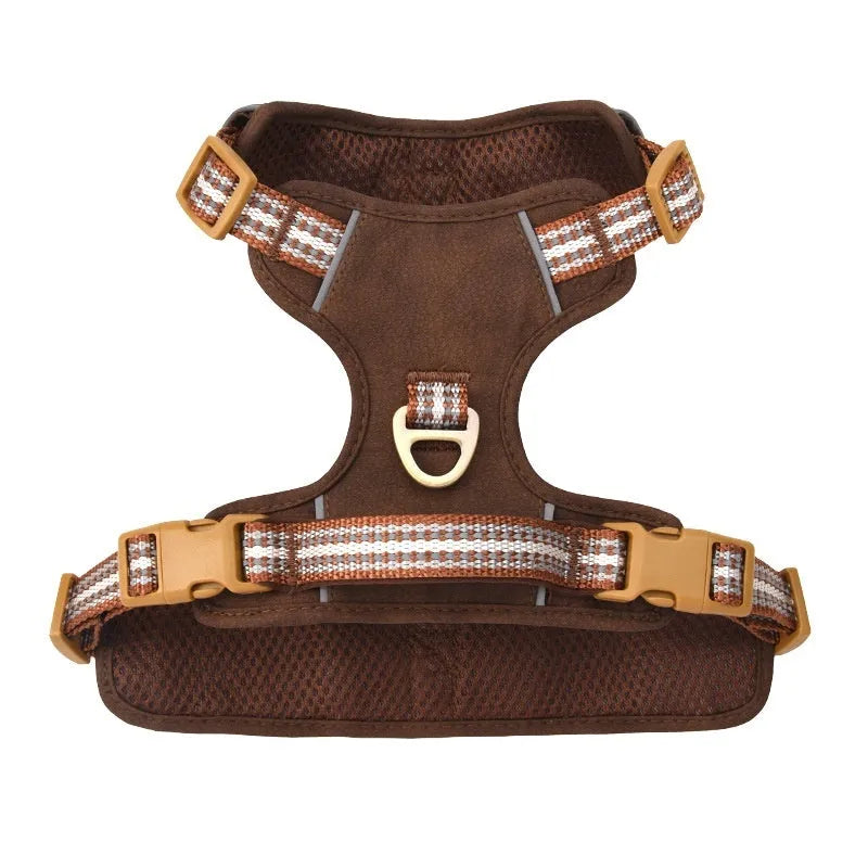 Brown leather dog harness with reflective strips and D-ring attachment on wooden background