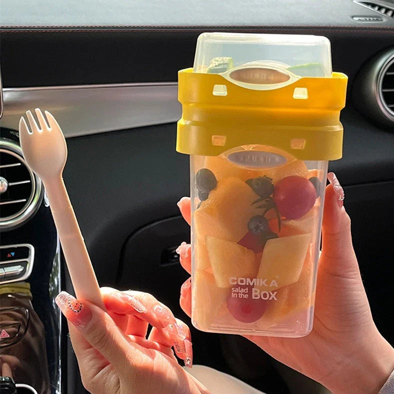 A portable bento box with two compartments for storing different types of food, such as salad, yogurt, oatmeal, and milkshake.