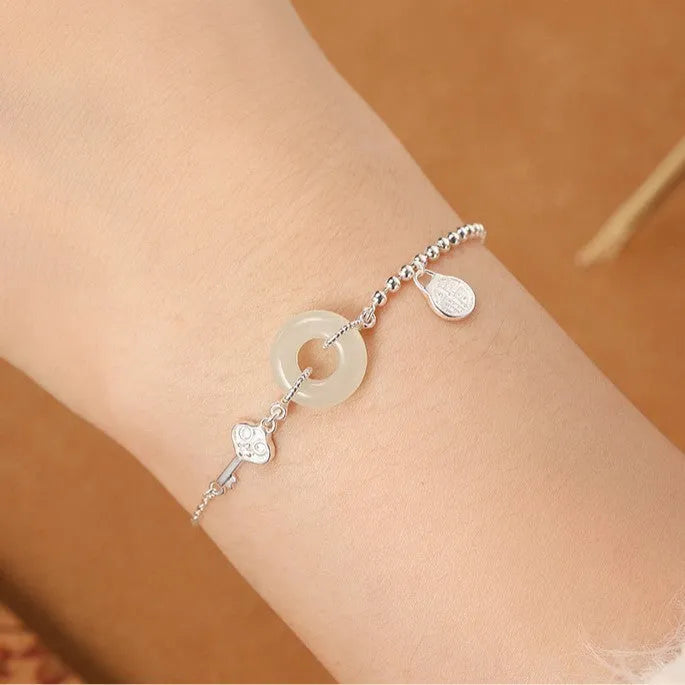 Women's silver bracelet with a geometric Hetian jade peace buckle charm on a chain.