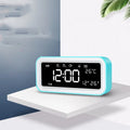 Blue rectangular multifunctional LED atmosphere light alarm clock with digital display on a wooden surface.