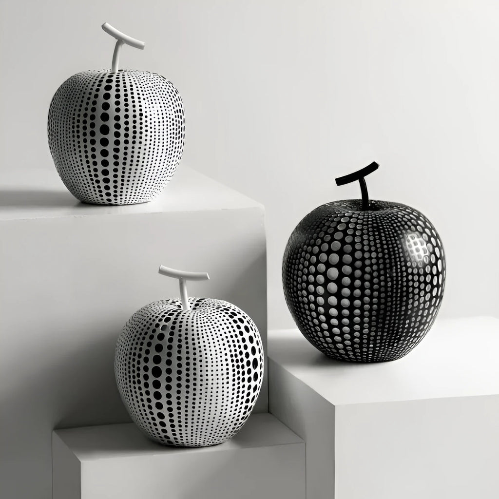 White and black resin apple and pear decorations showing high and low profile models on a wooden surface