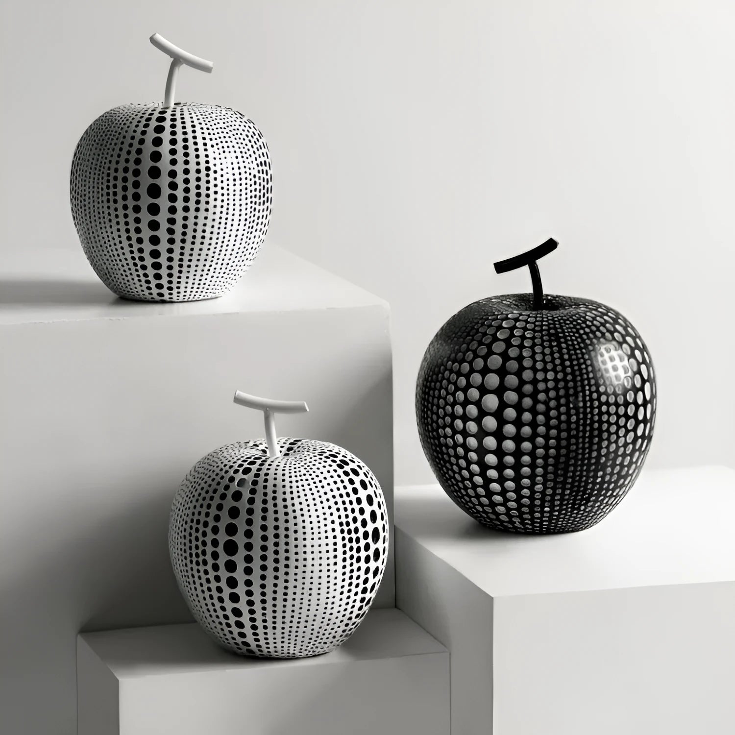 White and black resin apple and pear decorations showing high and low profile models on a wooden surface