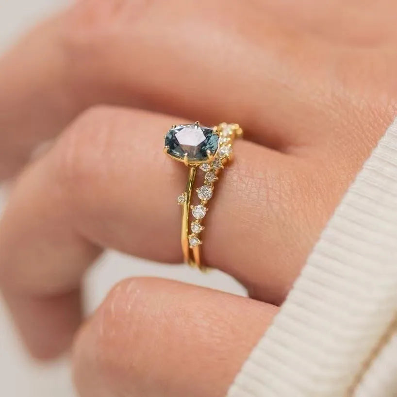 Close-up of a gold-plated floral ring with a central green zircon stone on a model's hand.