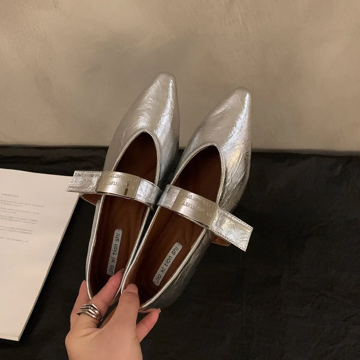 Women's black Mary Jane shoes with pointed toe, silver buckle, and low heel