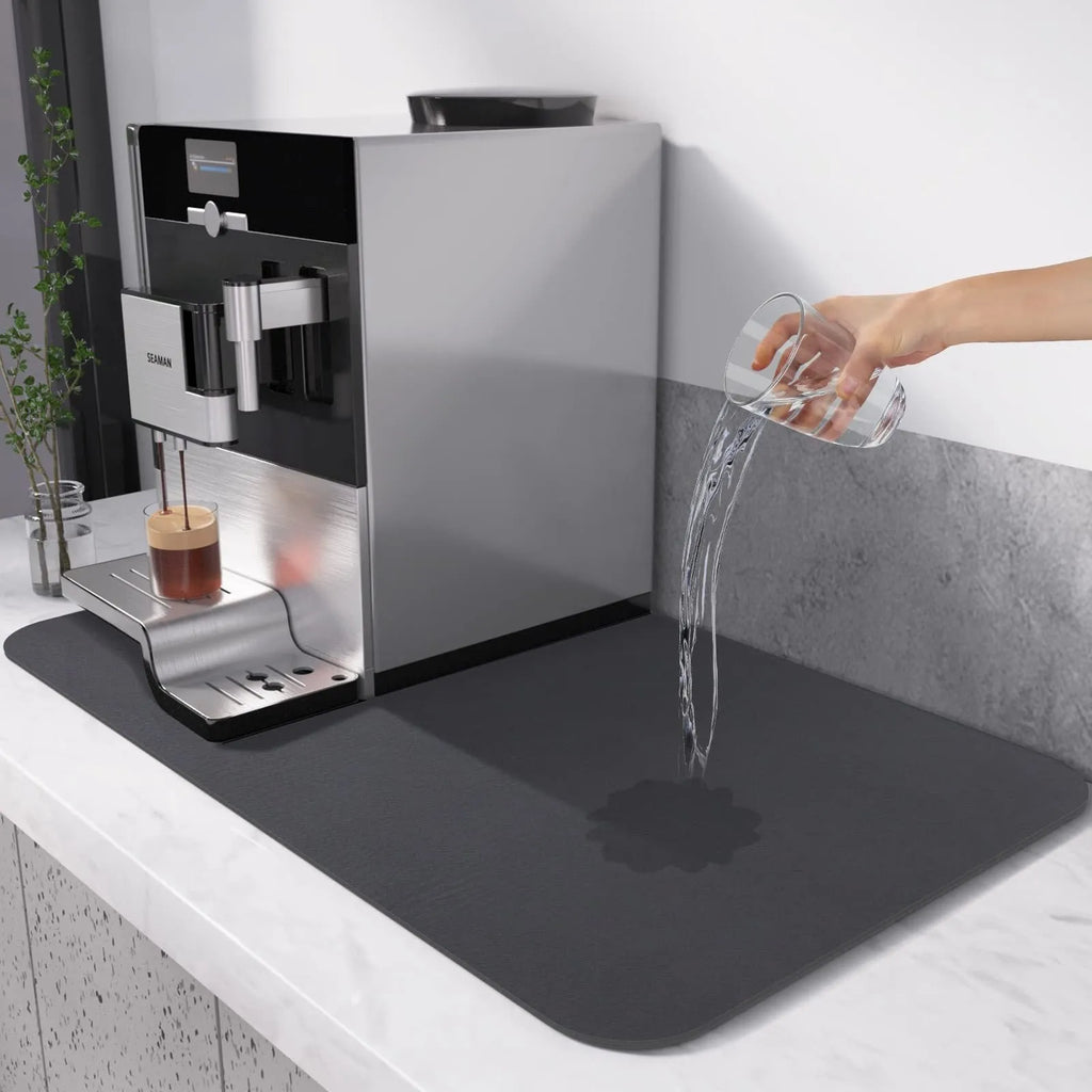 Black square rubber-backed kitchen drying mat on a countertop next to a coffee cup
