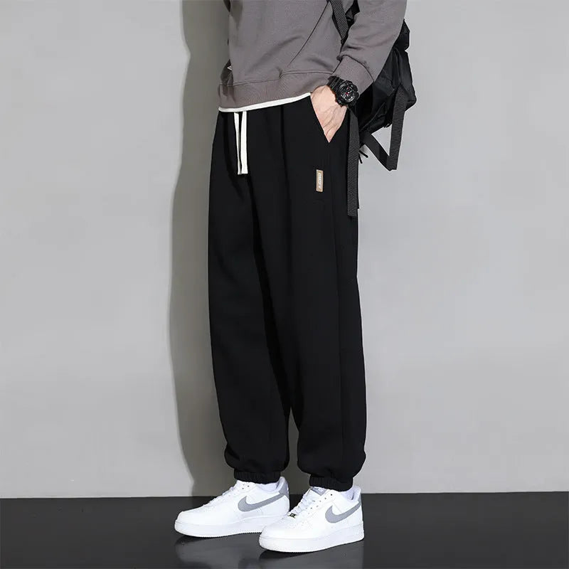 Men's loose grey cotton blend sports trousers with drawstring waist on a hanger.