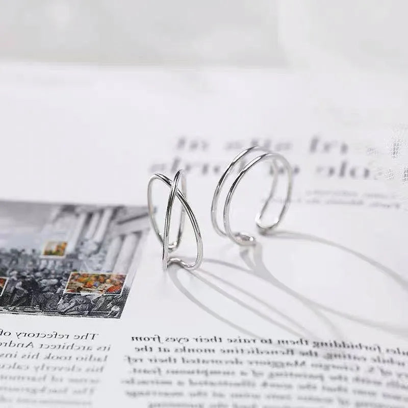 Silver-plated geometric cross ring with an adjustable opening on a copper base.