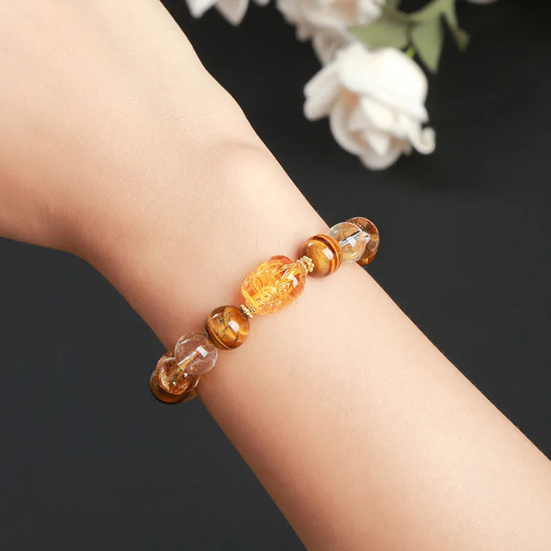 Close-up of a yellow tiger's eye and citrine gemstone bracelet with 10mm round beads and a steel clasp.
