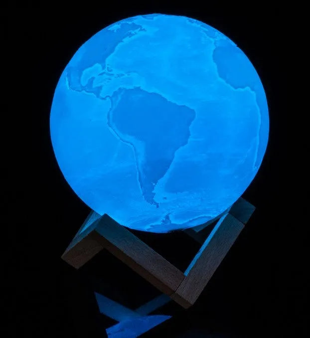 3D printed white moon lamp glowing on a wooden stand, showing detailed lunar craters.