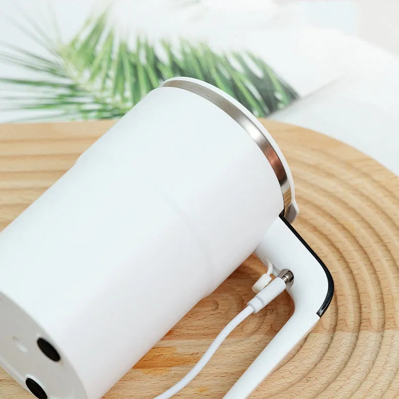 Black and white USB rechargeable electric stirring mug with LCD screen showing temperature, next to its magnetic stirrer.
