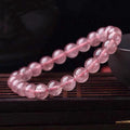Women's strawberry quartz crystal bracelet with polished beads on an elastic cord, shown in 6mm, 8mm, and 10mm sizes.