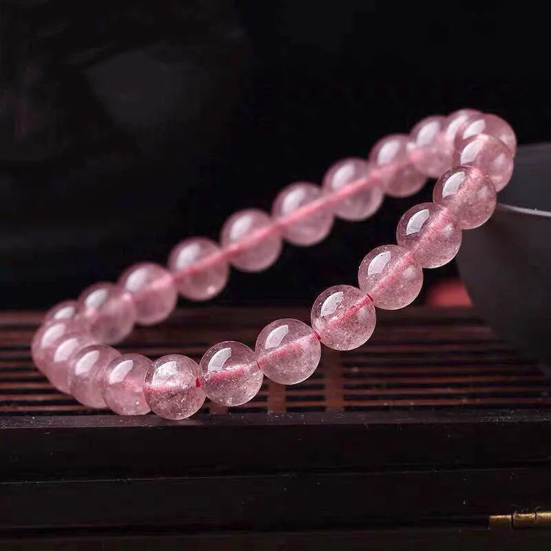 Women's strawberry quartz crystal bracelet with polished beads on an elastic cord, shown in 6mm, 8mm, and 10mm sizes.