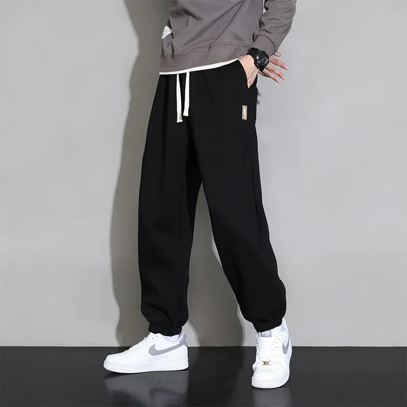 Men's loose grey cotton blend sports trousers with drawstring waist on a hanger.