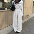 White striped loose-fit wide-leg trousers with a front zipper closure on a model.