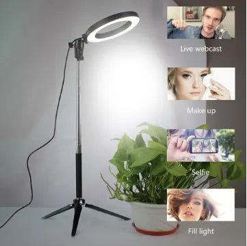 Black 20cm LED ring light kit with tripod, selfie stick, and phone clip on a desk