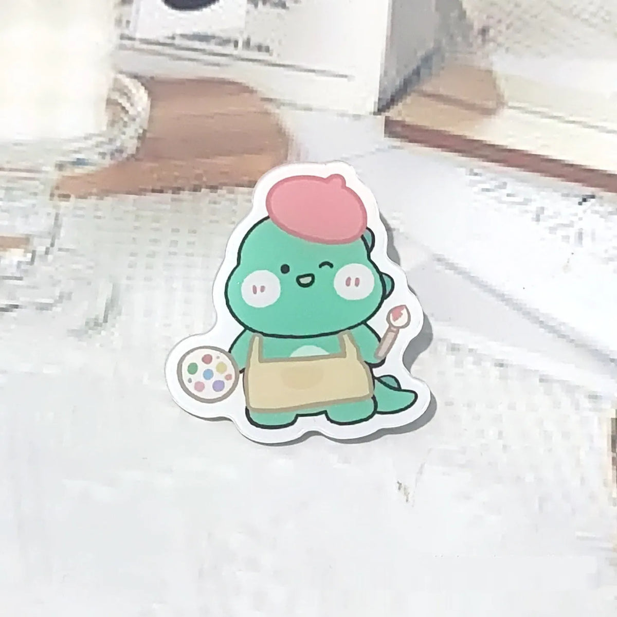 Cartoon dinosaur acrylic badge brooch with printed design and pin fastening, shown in one of twelve colour styles