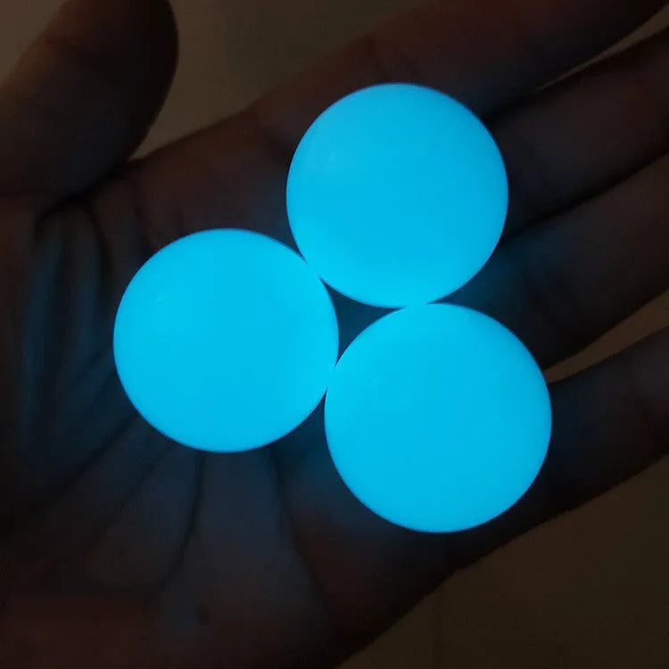 Luminous sticky ball toy in green colour glowing on a dark background, 4.5cm TPR squeeze ball for children