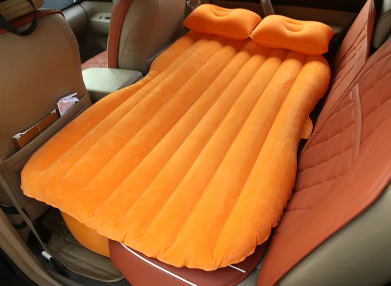 Inflatable car bed with flocking material shown in black colour, folded beside pillows and storage bag