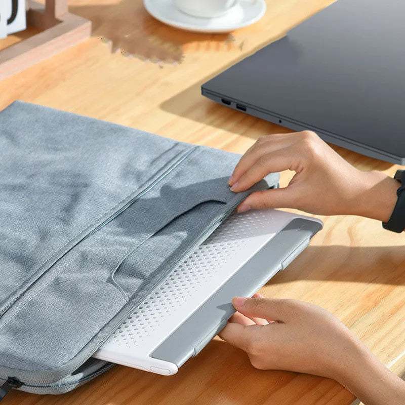 Portable black metal alloy laptop stand folded to 0.8mm thickness next to a notebook computer.