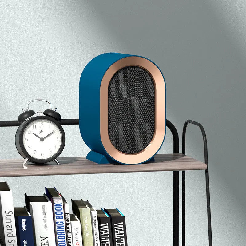 Compact black desktop electric fan heater with mechanical dial controls on a wooden desk.